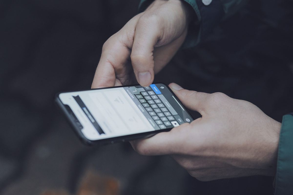 Mãos digitando uma mensagem no celular.